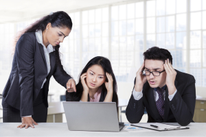 Bossy businesswoman pointing at laptop to show the mistake of her employees